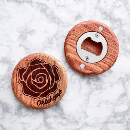 Flatlay of cherry wood bottle opener with engraved rose design and Oklahoma text on a marble background