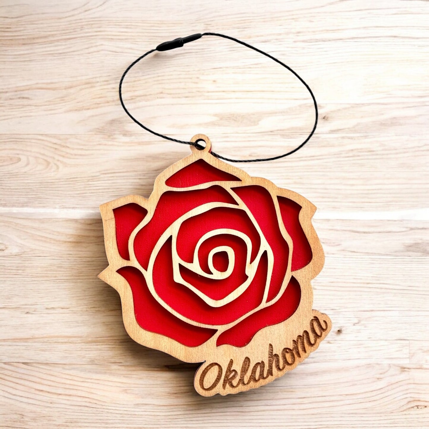 Flat lay of Oklahoma rose wooden ornament showing layered wood construction, red painted backing, and black hanging cord