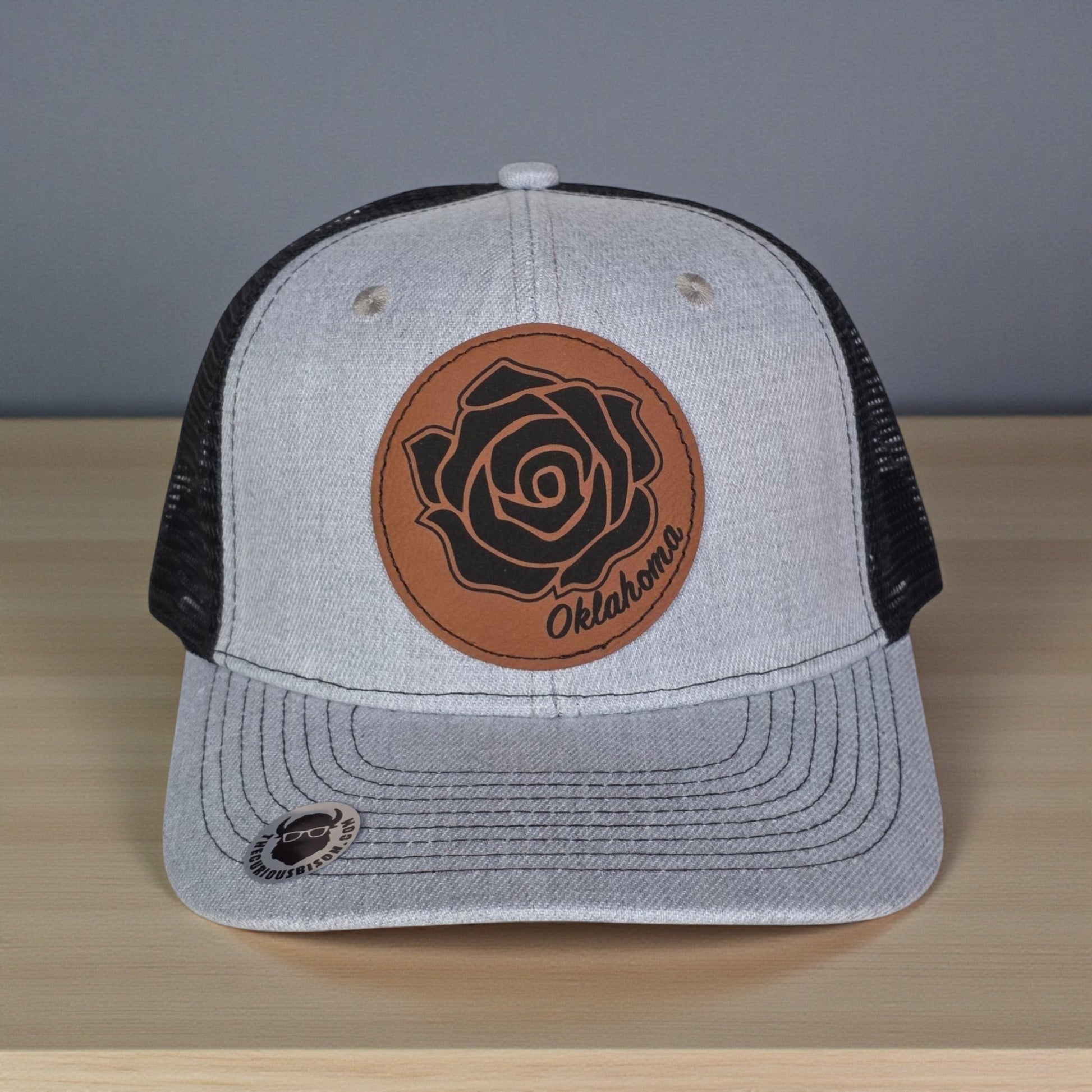 Close up of Oklahoma Rose Rock leatherette patch on trucker hat showing engraved floral rose rock design and stitching detail