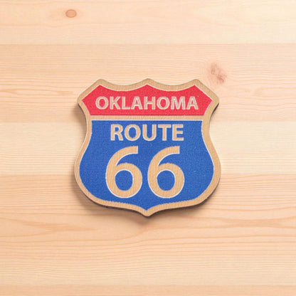 Oklahoma Route 66 wooden lapel pin photographed on light wood surface, printed Route 66 shield pin for Oklahoma travel gift