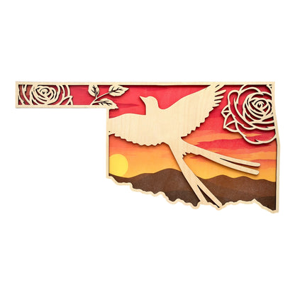 Front view of Oklahoma shaped layered wood wall art featuring Scissortail Flycatcher silhouette, Oklahoma roses, and sunset prairie landscape with warm orange and red sky colors