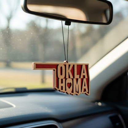 Wooden Oklahoma state word cutout car ornament hanging from rearview mirror, layered OKLAHOMA lettering inside state silhouette with bold red backing, lightweight auto accessory gift for Oklahoma locals, college fans, and Route 66 road trip travelers