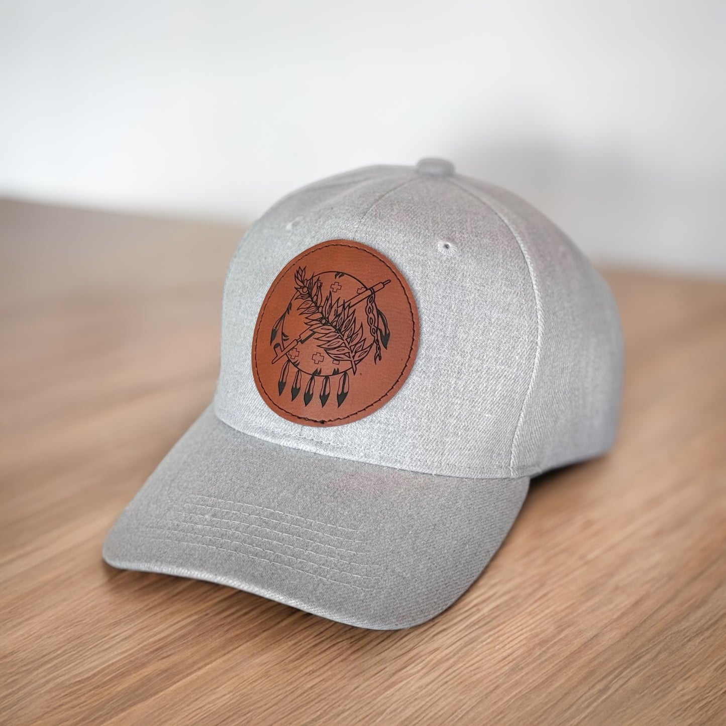 Angled view of gray Oklahoma symbol leather patch hat resting on wood surface, Oklahoma travel and souvenir hat