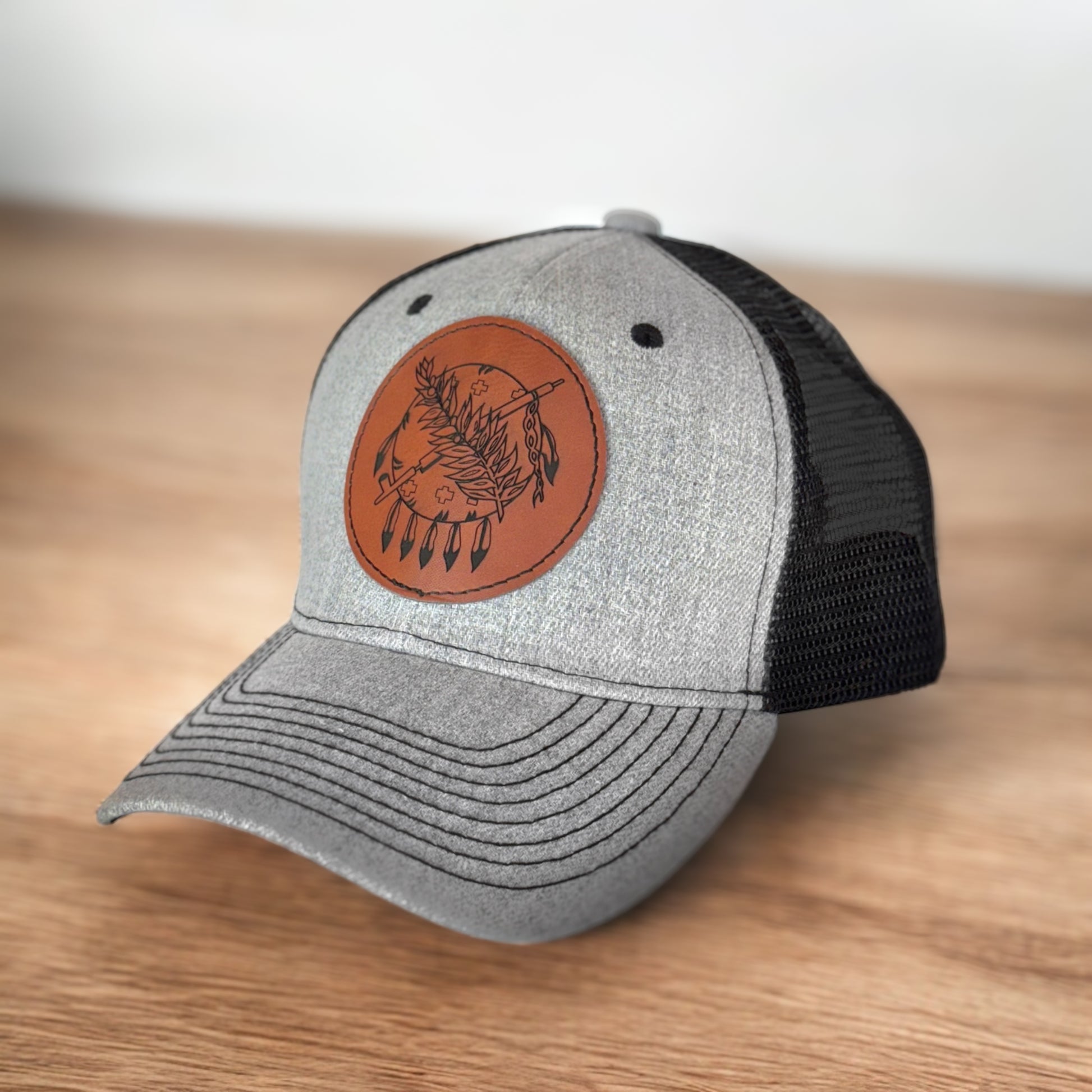 Angled view of gray and black Oklahoma symbol leather patch hat on wooden surface, Oklahoma gift hat