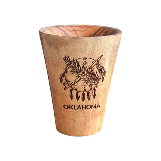 Oklahoma symbol olive wood shot glass with laser engraved Oklahoma emblem and OKLAHOMA text, solid olive wood shot glass photographed on white background, Oklahoma souvenir gift