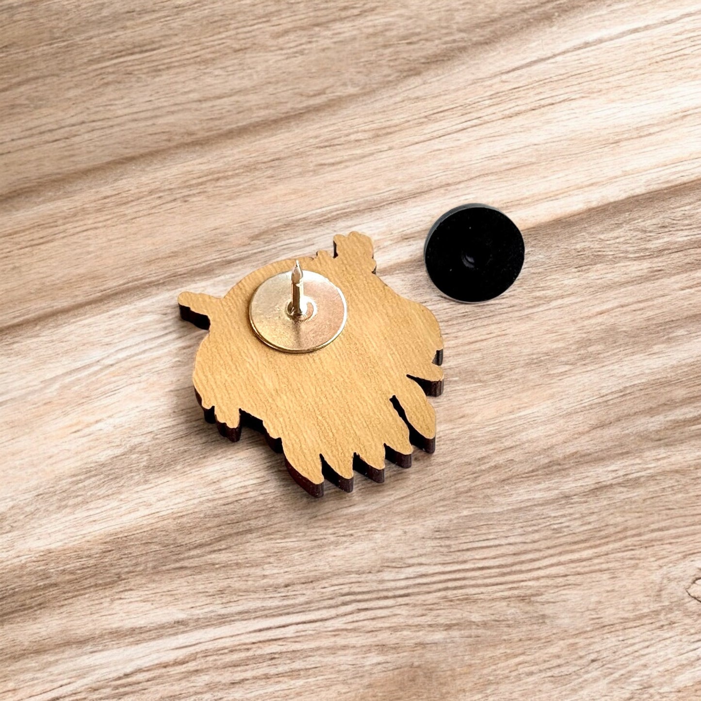 Back of Oklahoma symbol wooden pin showing metal post and black rubber pin back, lightweight wooden lapel pin for hats and jackets