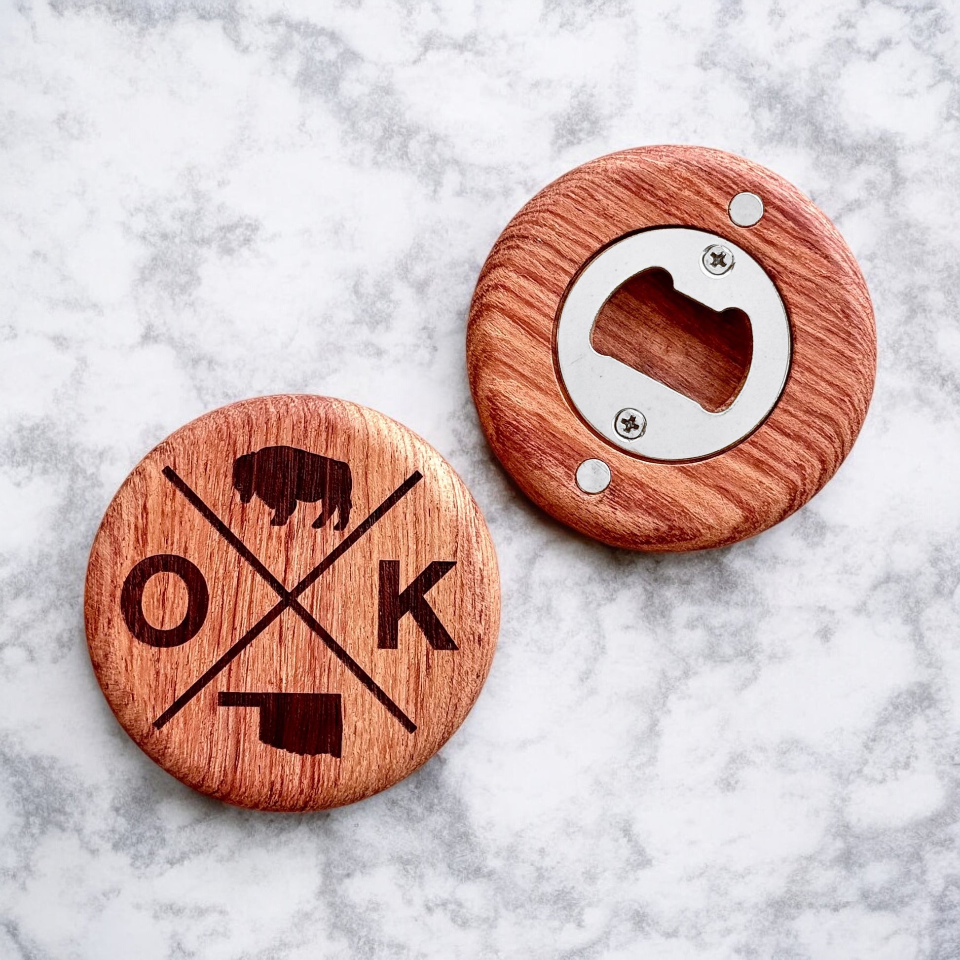 Flatlay of round cherry wood bottle opener featuring OK bison cross design and magnetic back