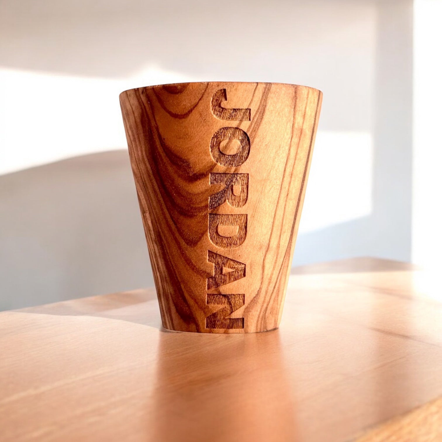 Close up of name engraving on olive wood shot glass, custom engraved wood barware gift