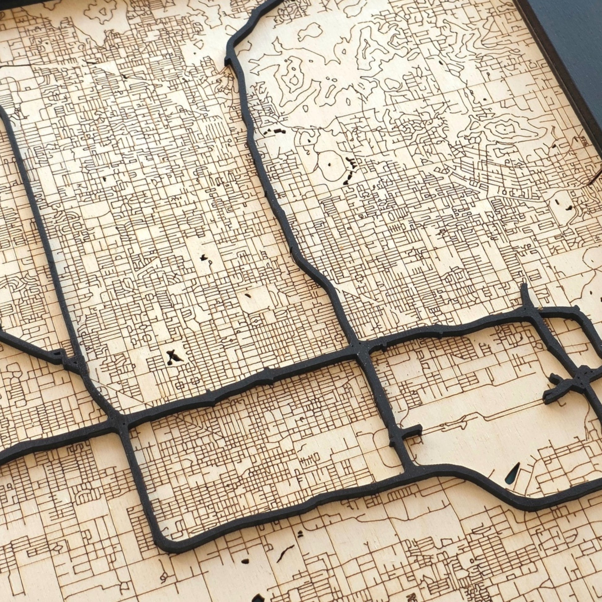 close up of Phoenix wood map showing detailed engraved streets and raised road layers with natural wood tones and dark contrast