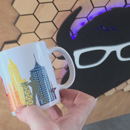 White ceramic mug with Tulsa skyline and rainbow-colored buildings