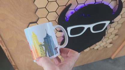 White ceramic mug with Tulsa skyline and rainbow-colored buildings