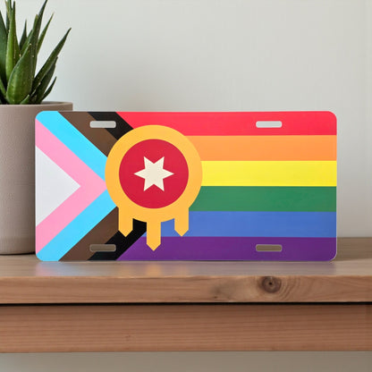 Rainbow Tulsa Flag Inclusive Pride vanity plate displayed on a wooden shelf, colorful LGBTQIA+ Tulsa souvenir by The Curious Bison.
