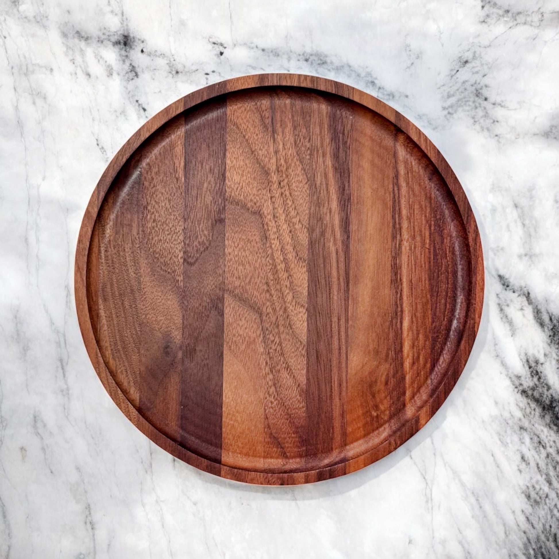 Top-down view of round walnut serving tray with natural wood grain and raised lip