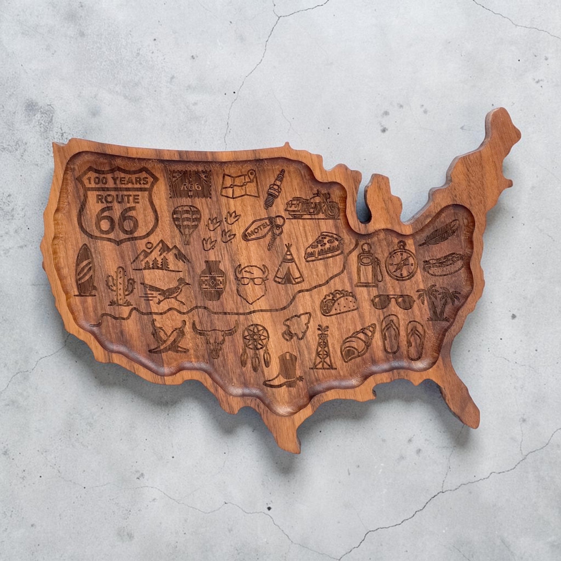 Flat lay of carved wooden United States shaped tray engraved with Route 66 inspired travel graphics and Americana symbols designed for home decor and travel souvenir display