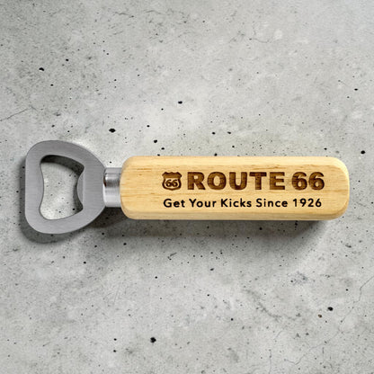 Engraved Route 66 wooden bottle opener displayed on gray concrete surface showing retro highway souvenir design and stainless steel bottle opener head