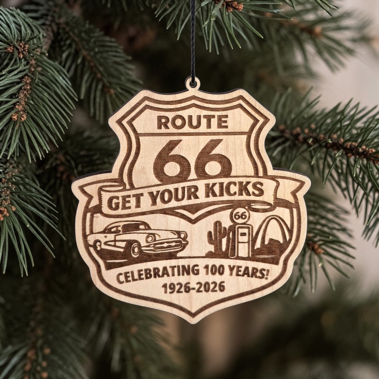 Route 66 Centennial wood ornament hanging on evergreen tree branch, laser engraved wooden Christmas ornament for Route 66 travelers and souvenir buyers