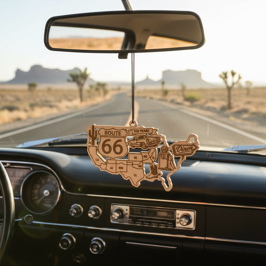 Route 66 centennial wooden ornament hanging from rearview mirror inside vintage car driving through desert highway, laser cut USA map ornament celebrating 100 years of Route 66 road trips across America