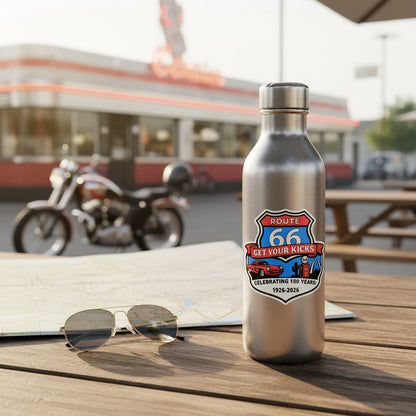 Stainless steel water bottle featuring Route 66 Centennial Get Your Kicks sticker on outdoor picnic table near roadside diner and motorcycle, showing travel souvenir and road trip lifestyle use