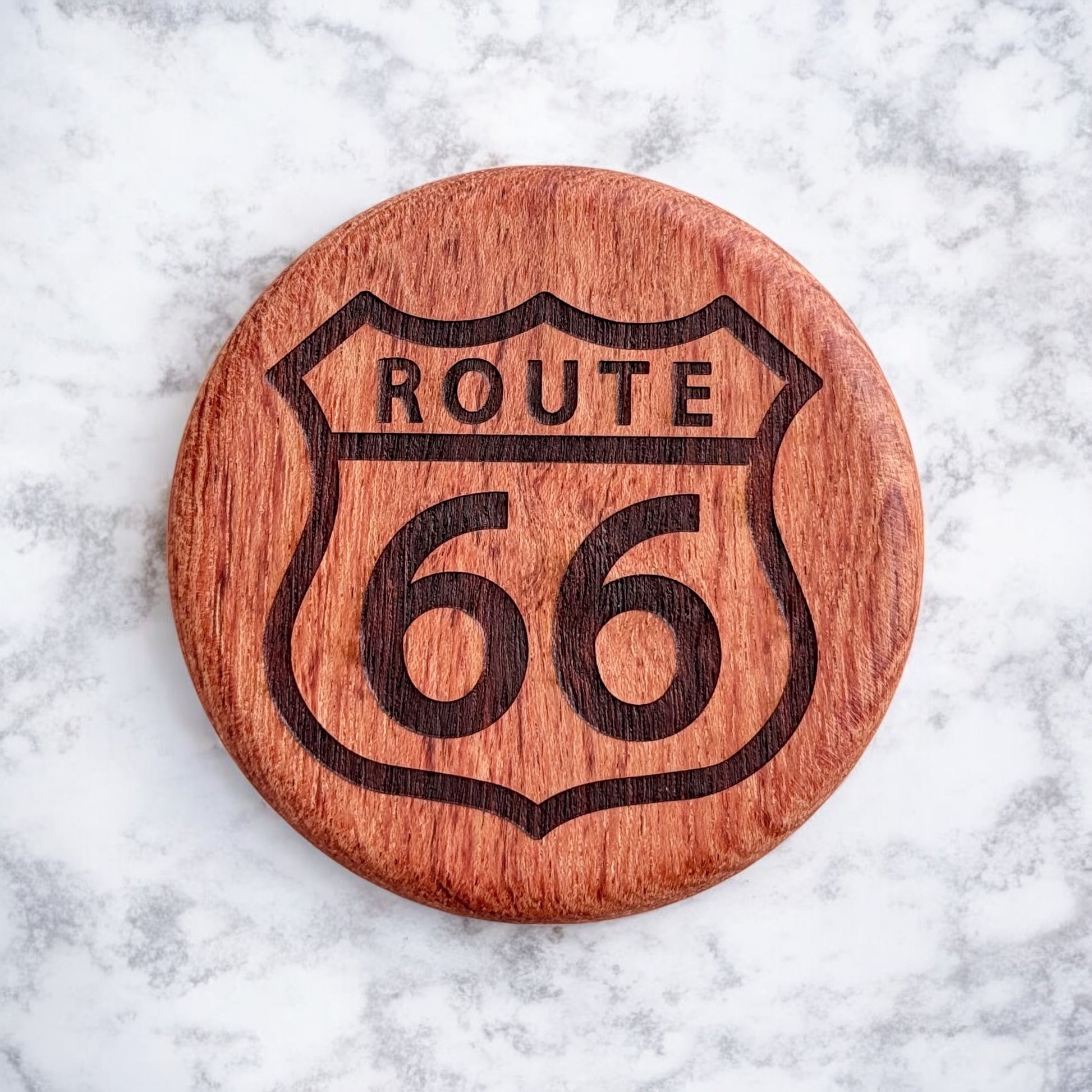 Front view of a round cherry wood bottle opener with a laser-engraved Route 66 highway sign design
