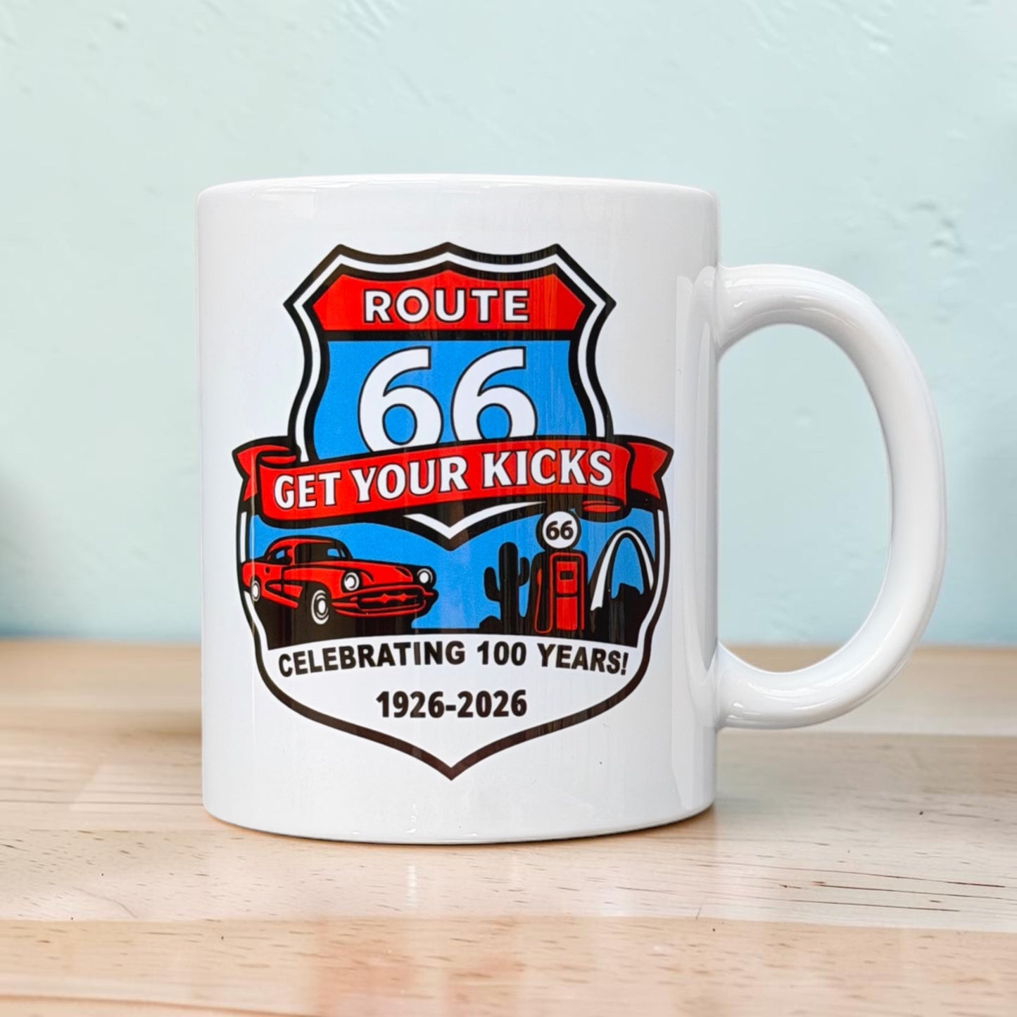 Side angle view of Route 66 Get Your Kicks ceramic mug with retro shield artwork celebrating the 1926-2026 Route 66 Centennial and featuring classic road trip inspired graphics