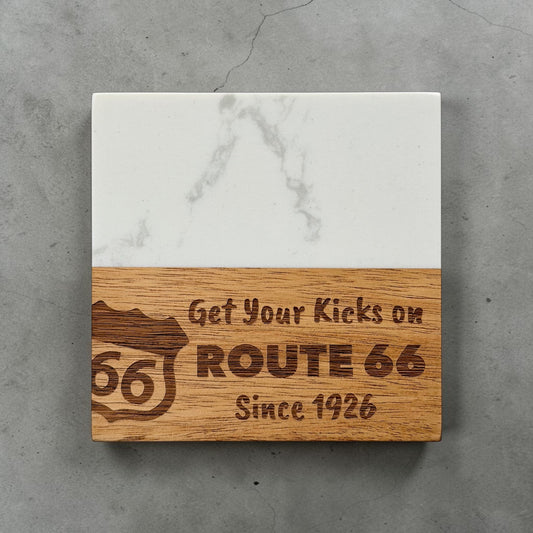 Route 66 marble and wood coaster photographed on gray concrete background showing engraved Route 66 shield and Since 1926 text, Oklahoma travel souvenir and road trip gift idea
