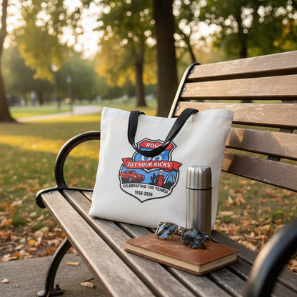Route 66 Centennial tote bag displayed on a park bench beside sunglasses, journal, and travel tumbler, showing practical road trip use for Route 66 travelers and Oklahoma tourists