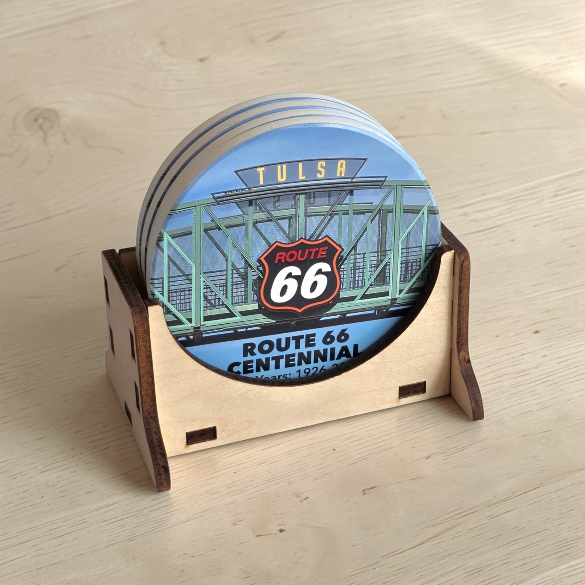 Route 66 Tulsa bridge sign coaster set in wood holder on light wood table, round ceramic Tulsa Route 66 souvenir coasters ready for display