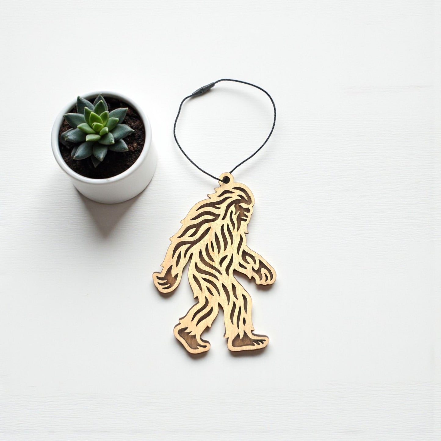 Flat lay of Bigfoot Sasquatch wooden ornament showing detailed cutout texture, natural wood ornament designed as a novelty gift or souvenir