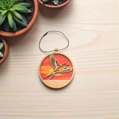 Flat lay of Oklahoma scissor-tailed flycatcher wooden ornament on light wood surface, layered wood ornament showing bird in flight with sunset colors for Oklahoma gift or travel souvenir