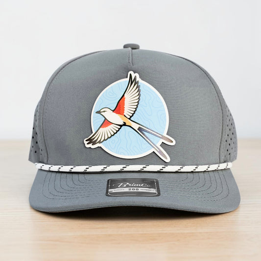 Close front view of Oklahoma scissortail performance golf hat featuring a colorful state bird patch over a blue topographic pattern with gray crown and rope detail