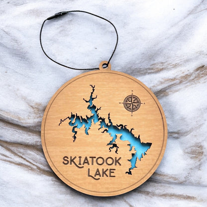 Skiatook Lake layered wooden ornament shown on marble surface, engraved lake name with blue painted water layer visible through cutout map