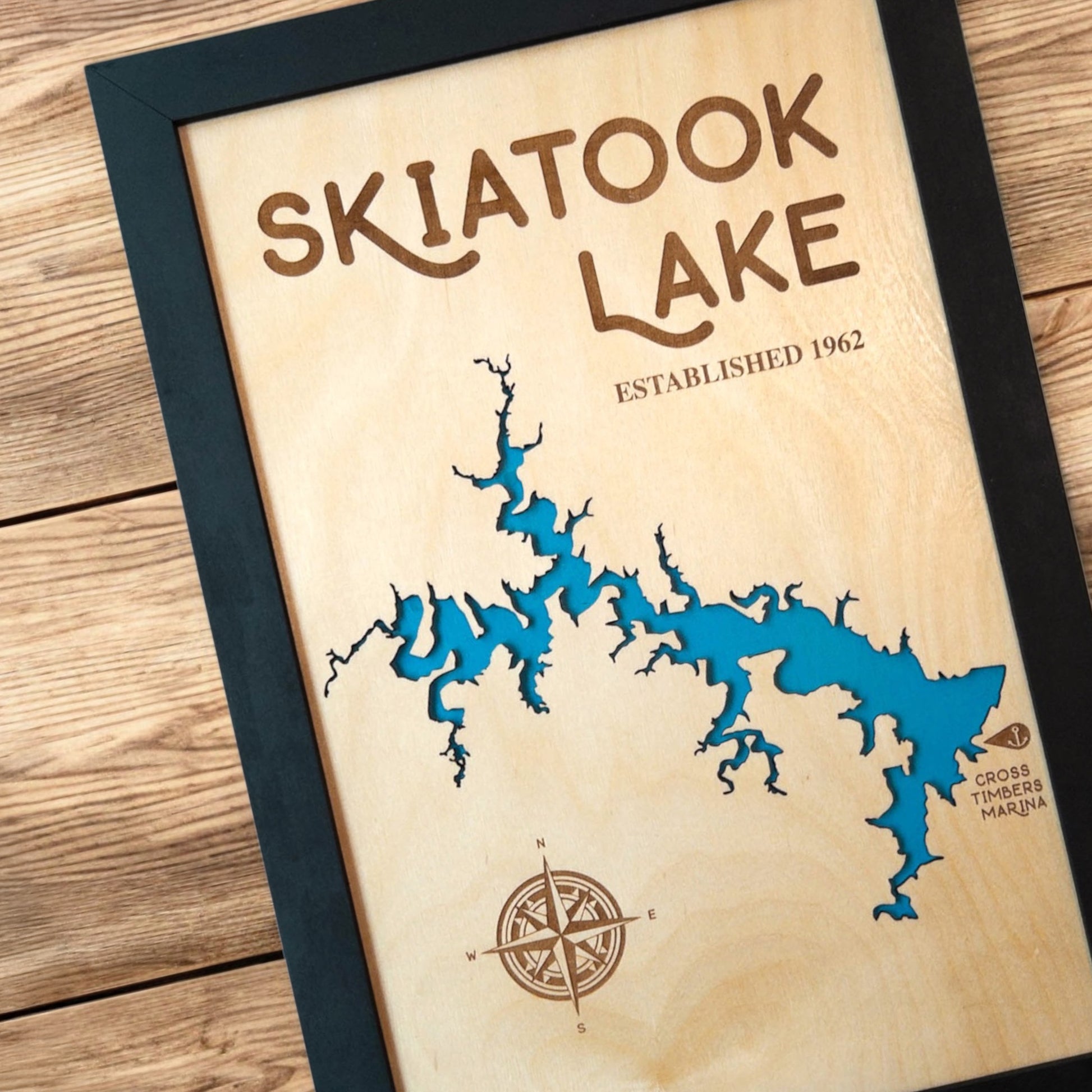 Close up of Skiatook Lake wood map showing blue lake backing, engraved compass rose, and shoreline detail