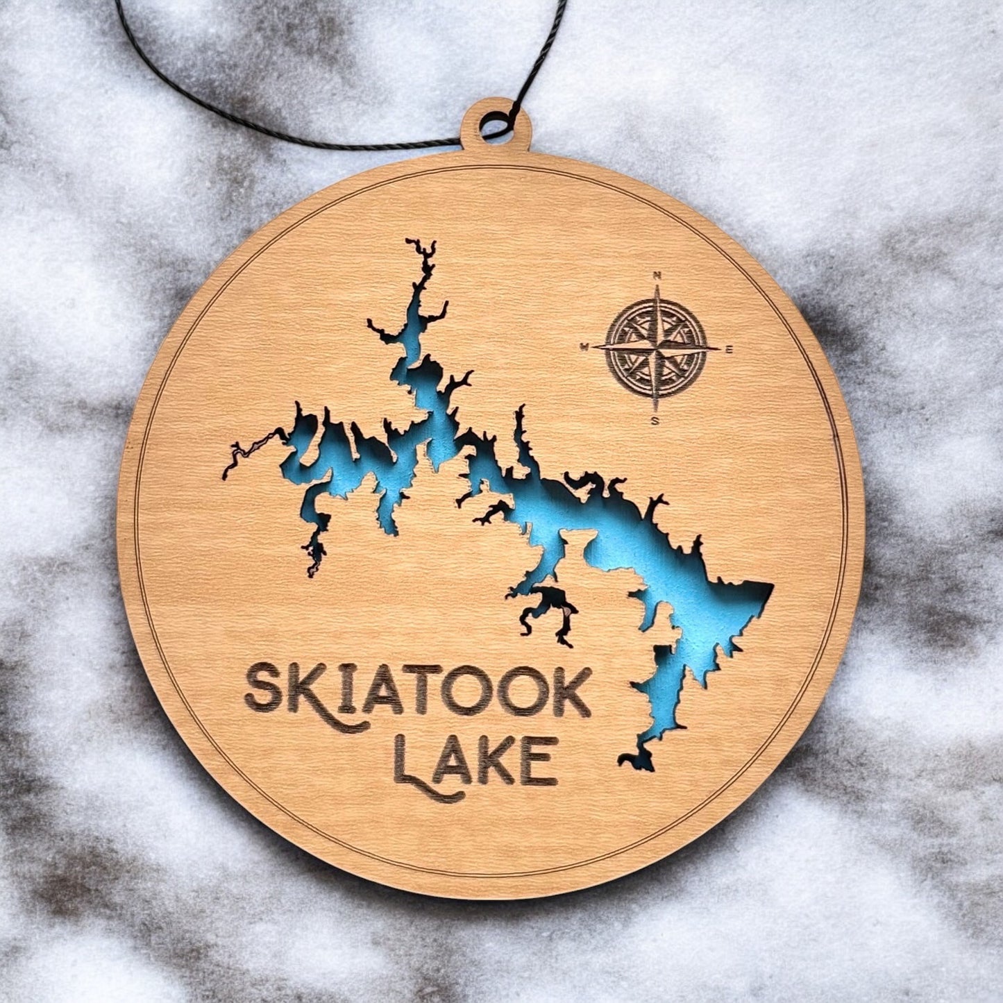 Close up of Skiatook Lake wooden map ornament showing laser cut shoreline detail, engraved compass, and painted blue water layer