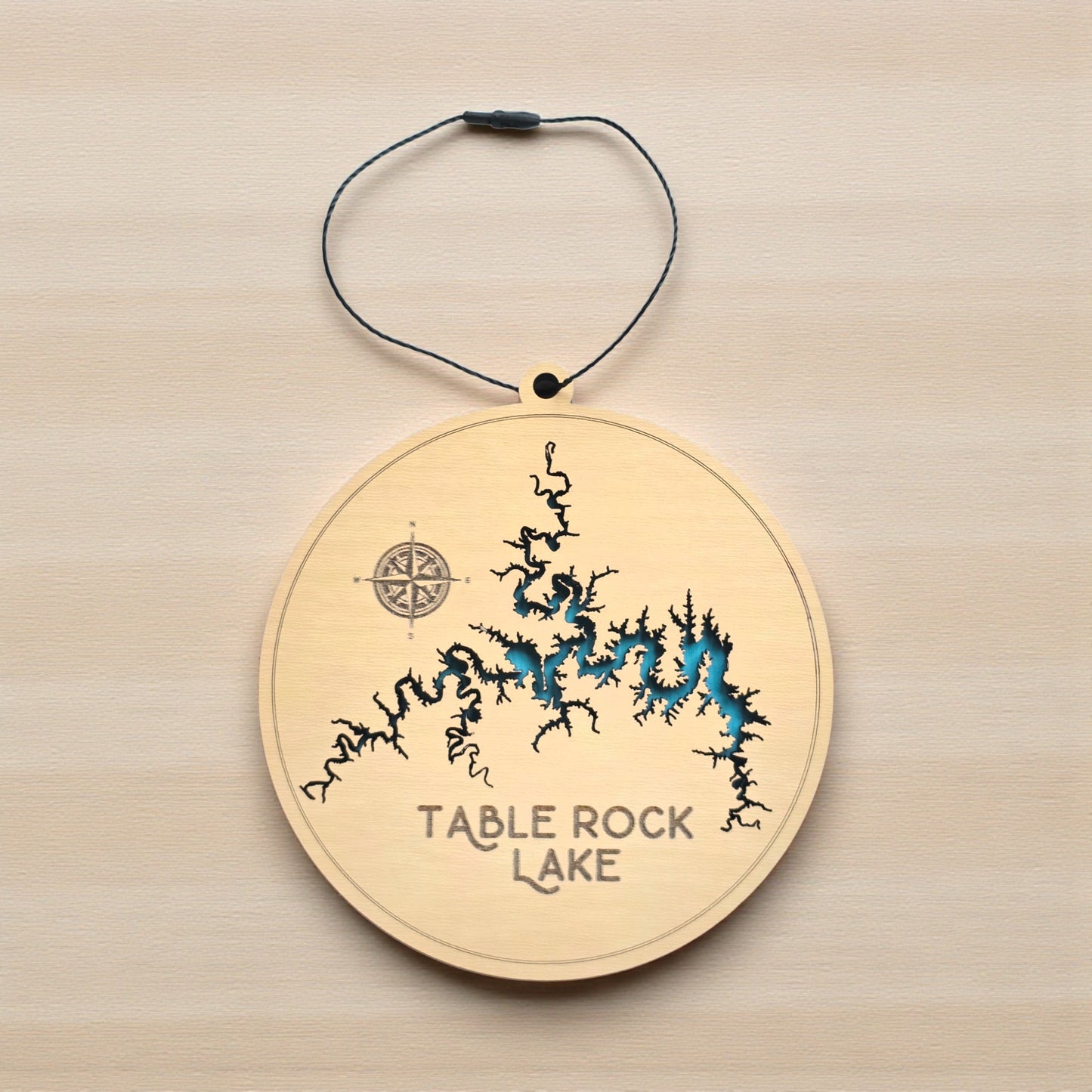 Flat lay of Table Rock Lake in Missouri layered wooden ornament showing engraved lake name, compass detail, and blue painted water layer beneath laser cut wood top
