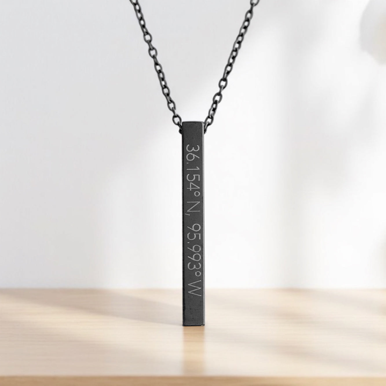 Black stainless steel Tulsa coordinates necklace engraved with 36.154°N, 95.993°W, standing upright against a soft background.