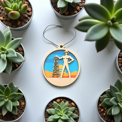 Flat lay of Tulsa Golden Driller wooden ornament on light surface, layered wood Tulsa landmark ornament with colorful sunset background for Oklahoma gift