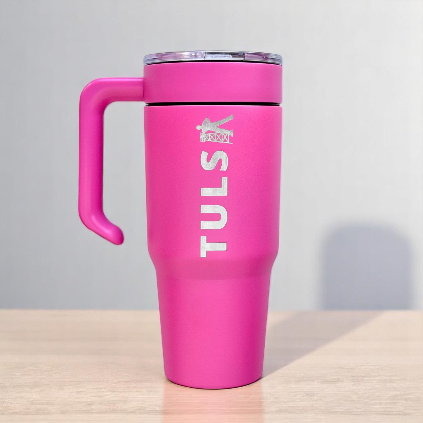 Pink Tulsa Driller 30oz tumbler standing on table with clear lid and handle, insulated stainless steel Tulsa travel cup
