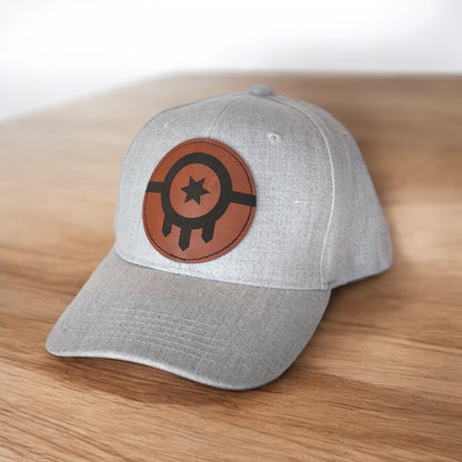 Angled view of gray Tulsa flag leather patch hat on wooden surface, Oklahoma travel and souvenir hat