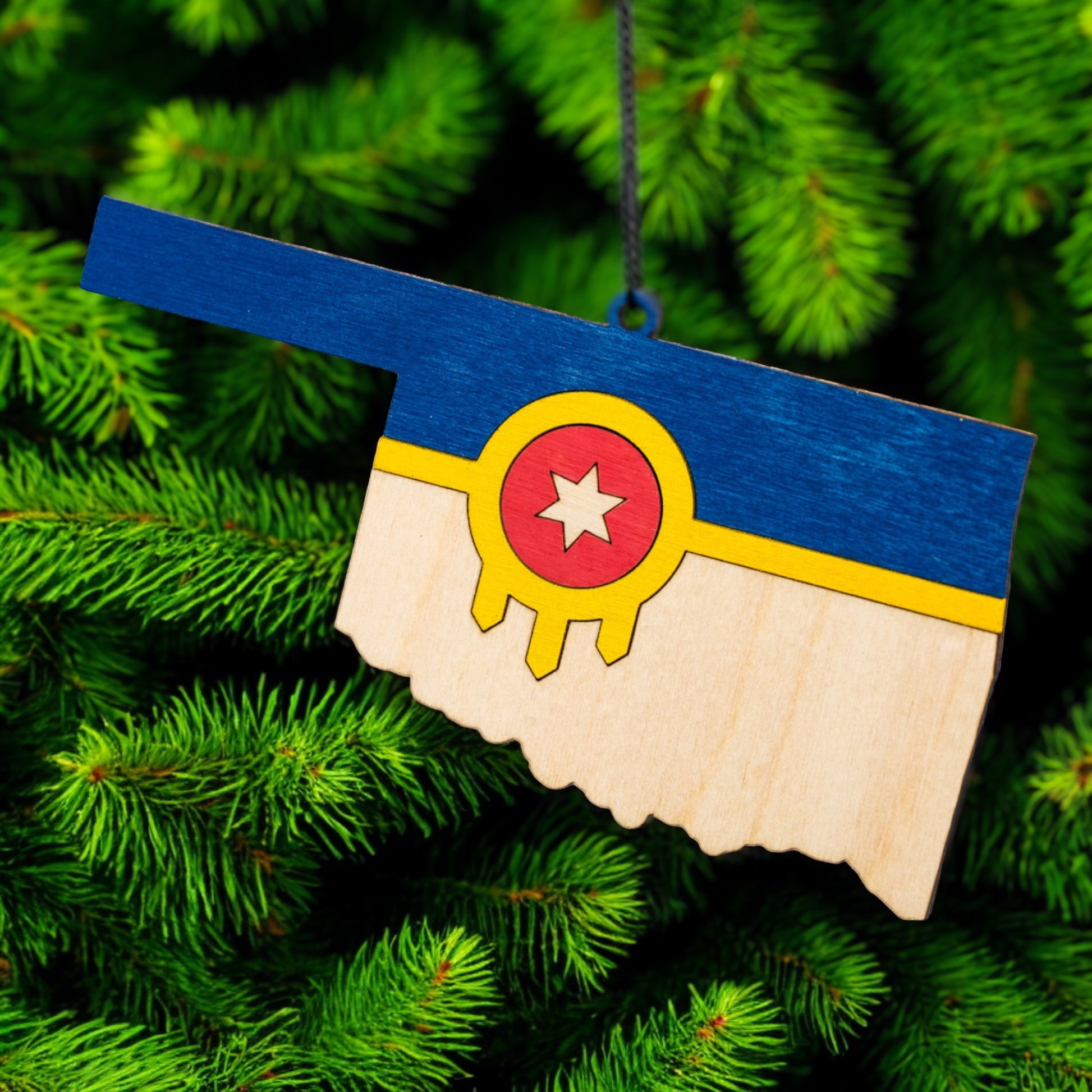 Tulsa flag Oklahoma ornament hanging on a green Christmas tree branch