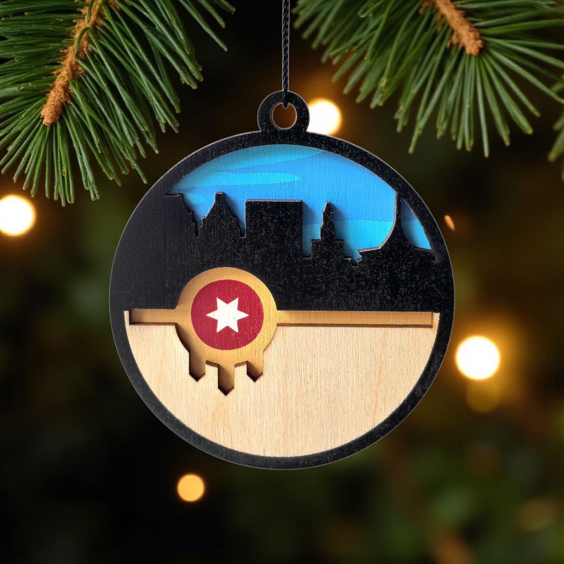 Tulsa flag skyline wooden ornament hanging on evergreen tree, layered wood Tulsa skyline ornament used as Oklahoma Christmas decor or Route 66 souvenir