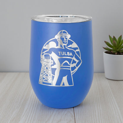 Blue Tulsa Golden Driller 12oz wine tumbler standing on table, engraved Oklahoma drinkware used as Tulsa gift or travel souvenir