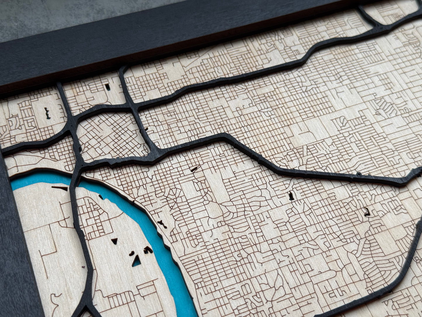 Close up of raised black road layers on Tulsa wooden city map, showing laser cut roads and engraved neighborhood detail