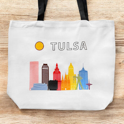 Large Tulsa LGBTQIA pride skyline tote bag shown flat on wood surface with colorful Tulsa landmark illustration