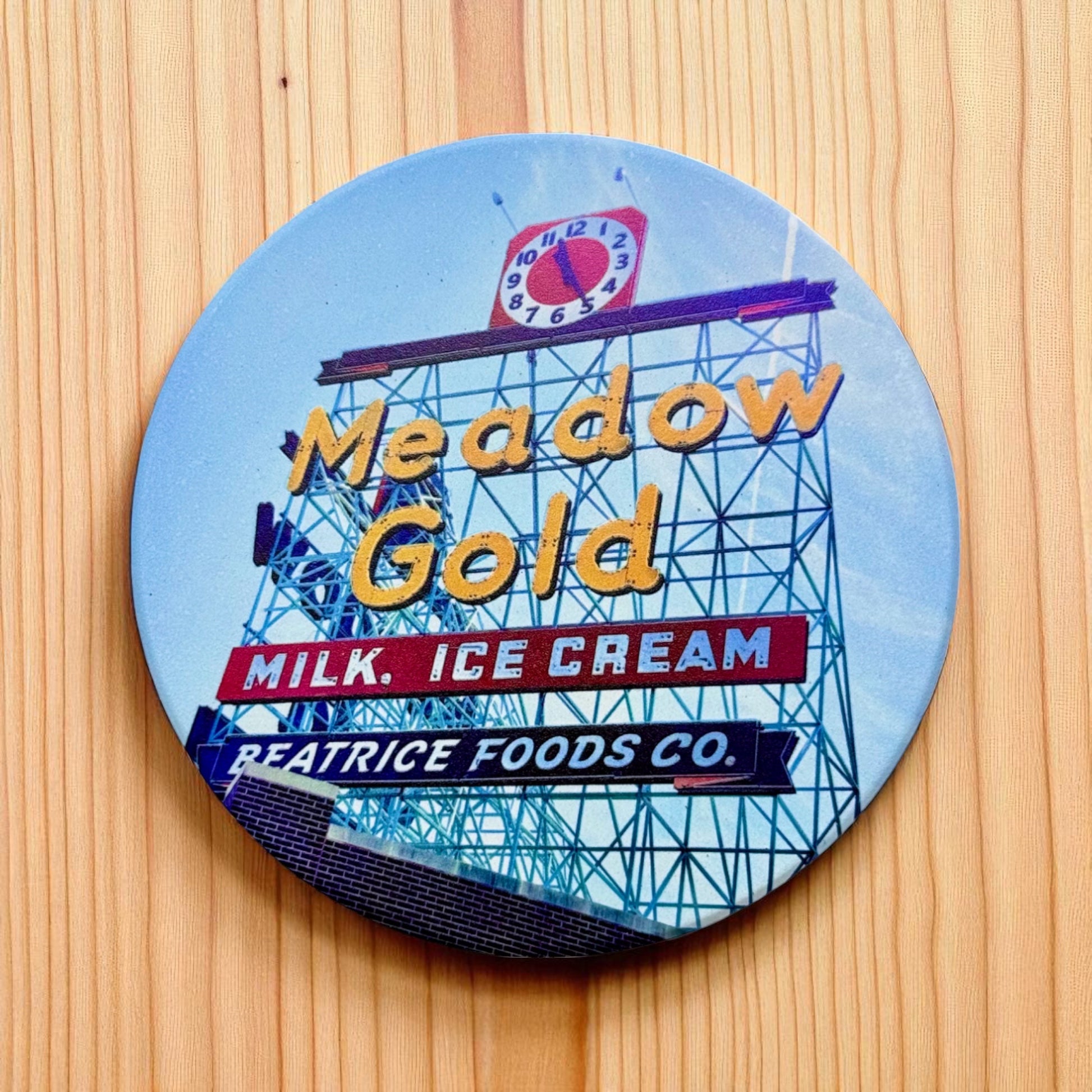 Tulsa Meadow Gold sign ceramic coaster displayed on a wood surface, round ceramic Route 66 Tulsa landmark coaster used as an Oklahoma gift or travel souvenir