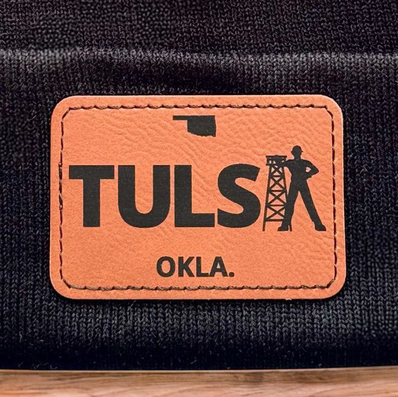 Close up of Tulsa Oklahoma leatherette patch showing TULSA text and oil derrick design on knit beanie