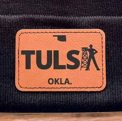 Close up of Tulsa Oklahoma leatherette patch showing TULSA text and oil derrick design on knit beanie
