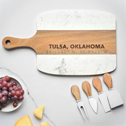 Tulsa Oklahoma charcuterie board with engraved city coordinates on acacia wood center strip, white marble serving board with four piece cheese knife set, stylish Tulsa gift for housewarming or souvenir use