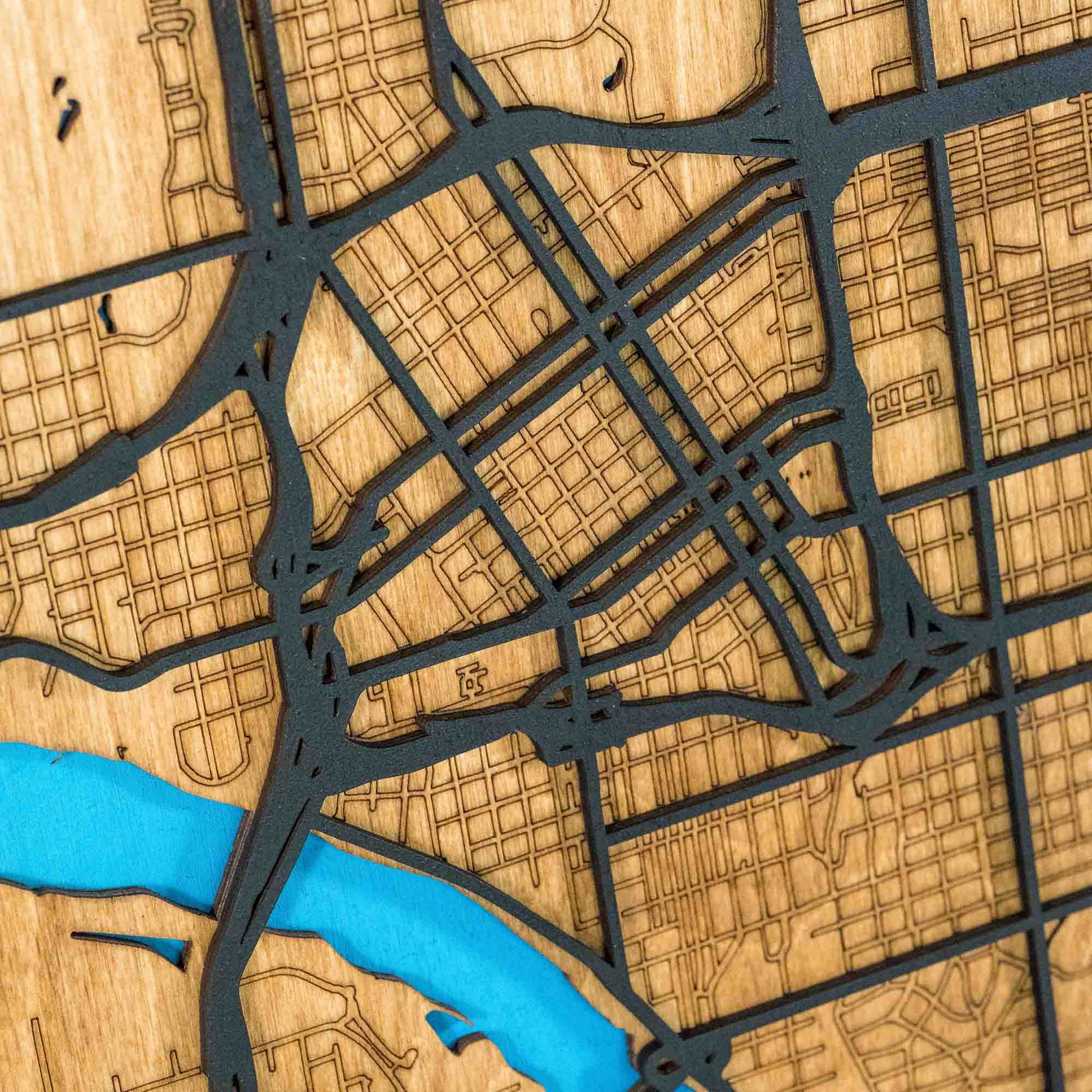 Close-up of intricate street engravings on the Tulsa, Oklahoma, wooden map with a focus on the river.