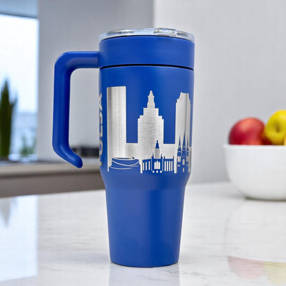 Blue Tulsa skyline 30oz insulated tumbler standing on kitchen counter with engraved Tulsa buildings and removable handle