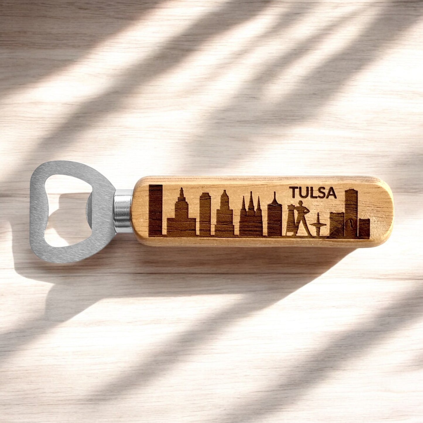 Tulsa skyline bottle opener with engraved wooden handle photographed on light wood surface, Tulsa souvenir and Oklahoma themed bar accessory